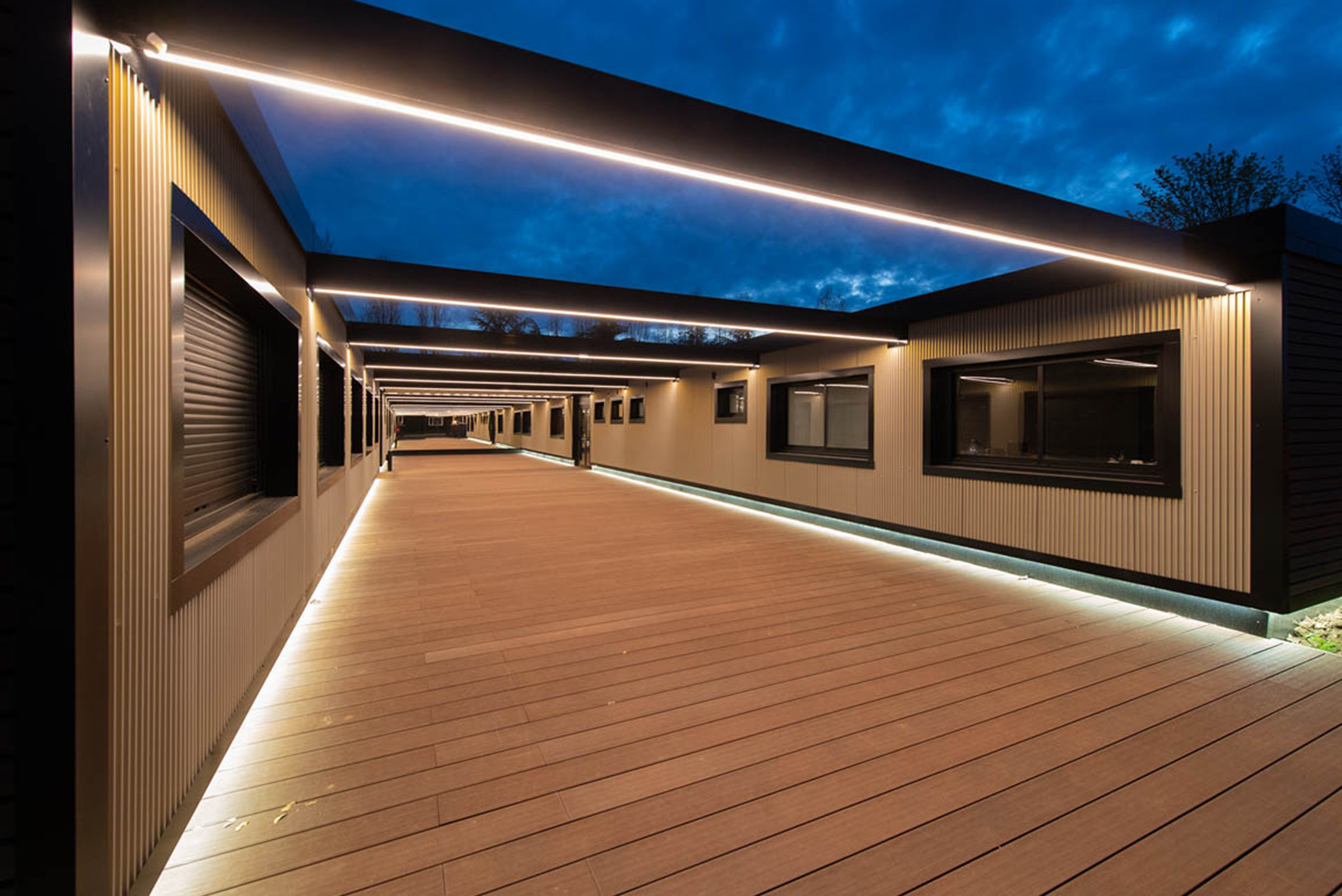allée intérieure en bois entre deux bâtiments modulaires algeco avec éclairage de nuit