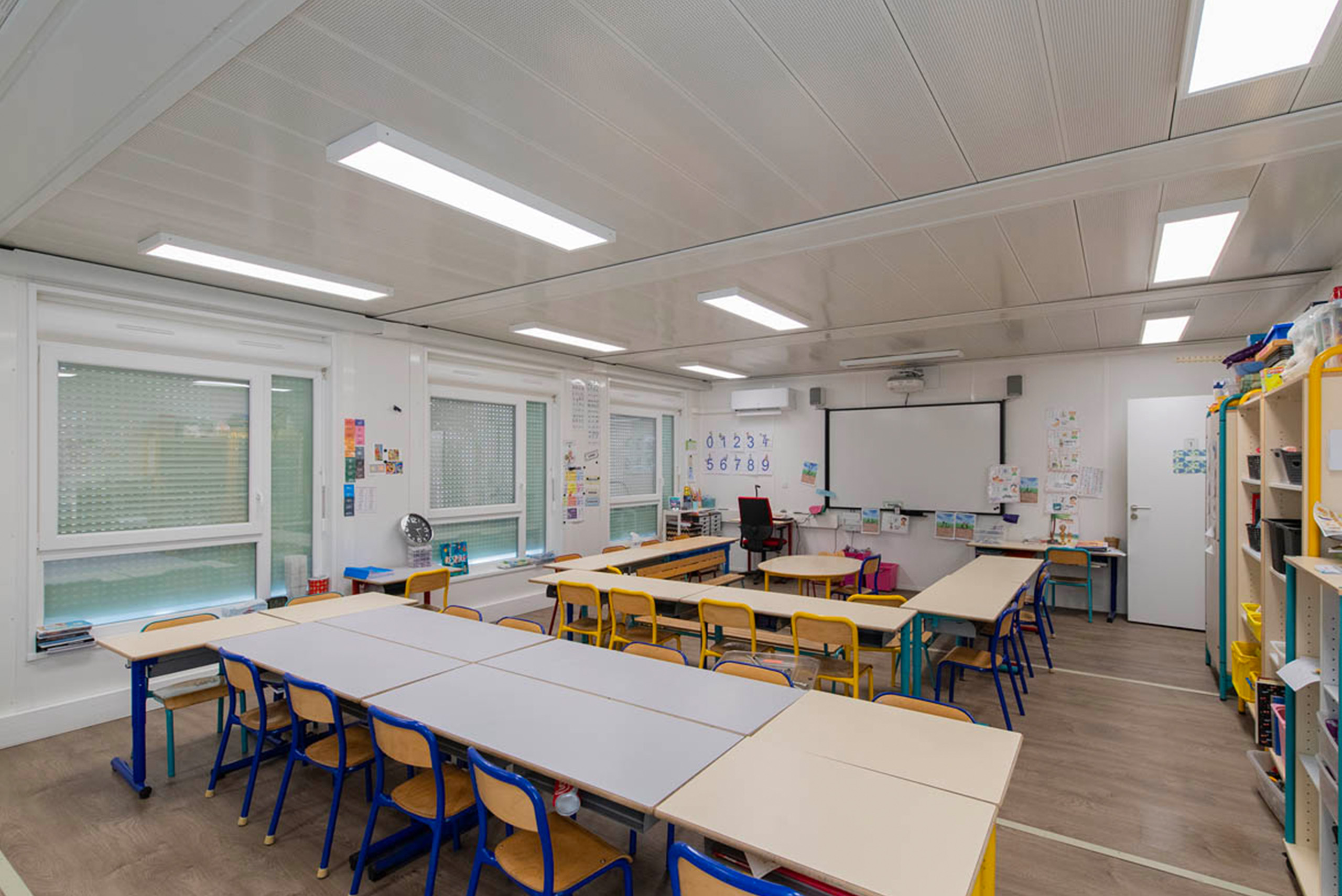 Salle de classe modulaire ALGECO® avec tables et chaises organisés en rectangle et en carré