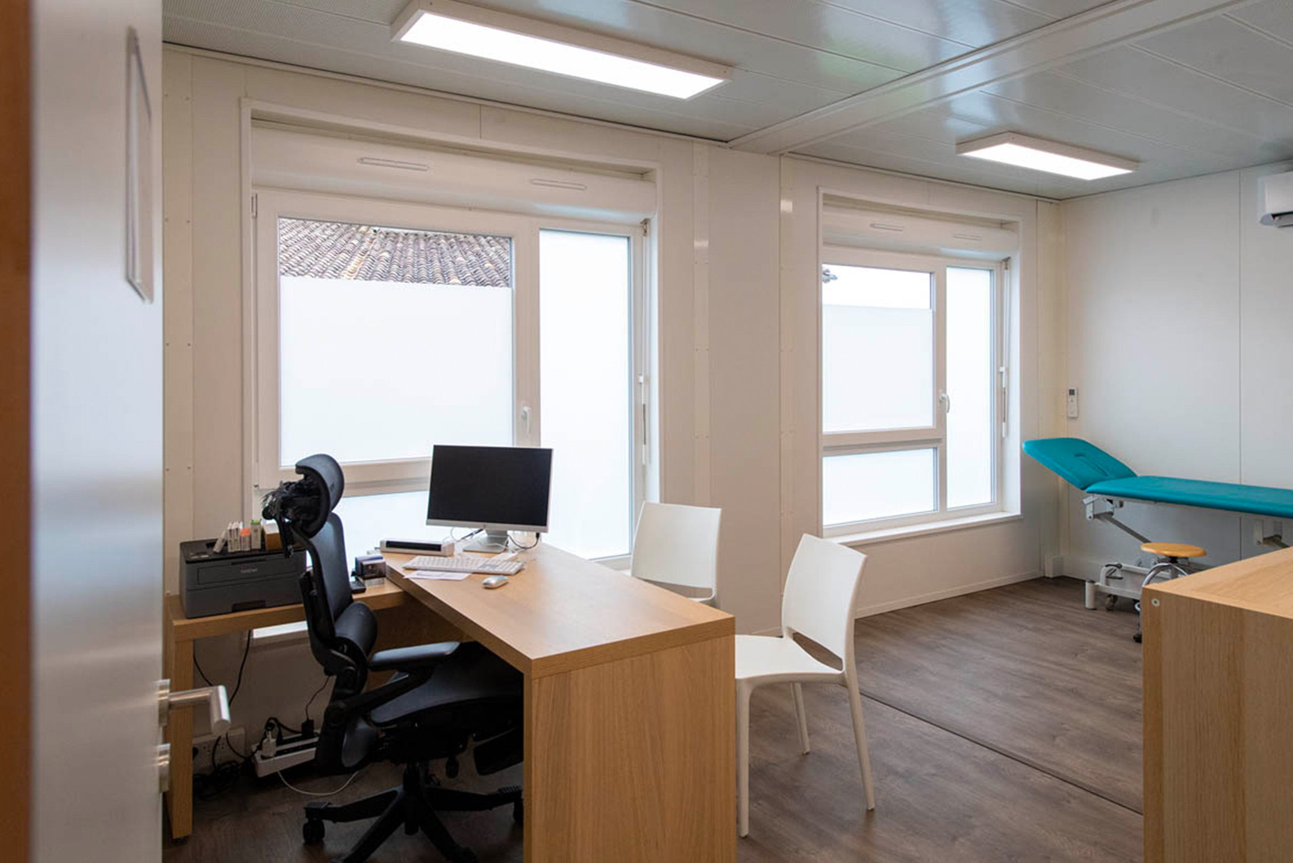 Cabinet médical modulaire ALGECO® avec banc, bureaux, ordinateur, climatisation et fenêtre entrée sur la droite