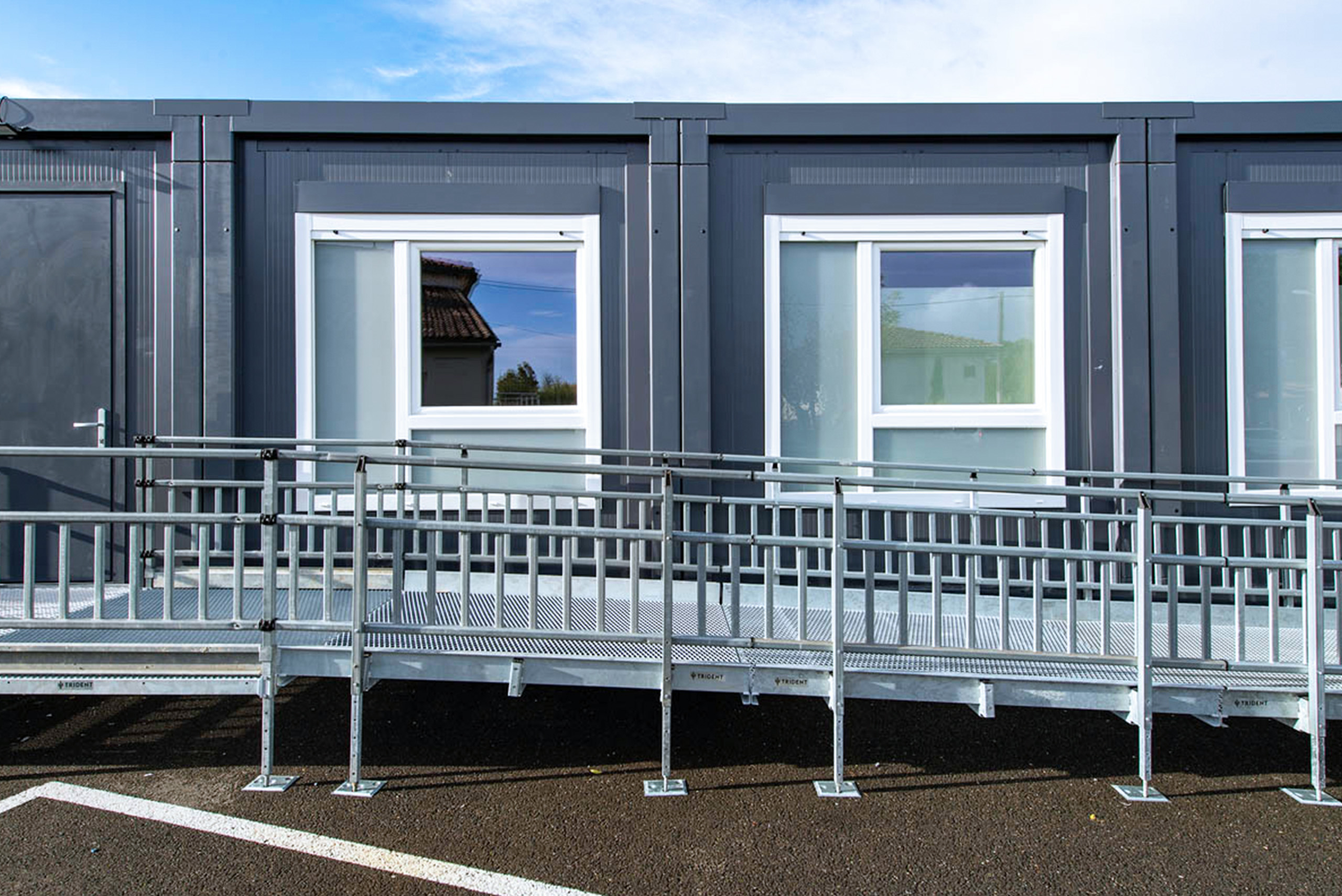Vue de face de quatre modules ALGECO® alignés en plein air avec fenêtre et rampe d’accès