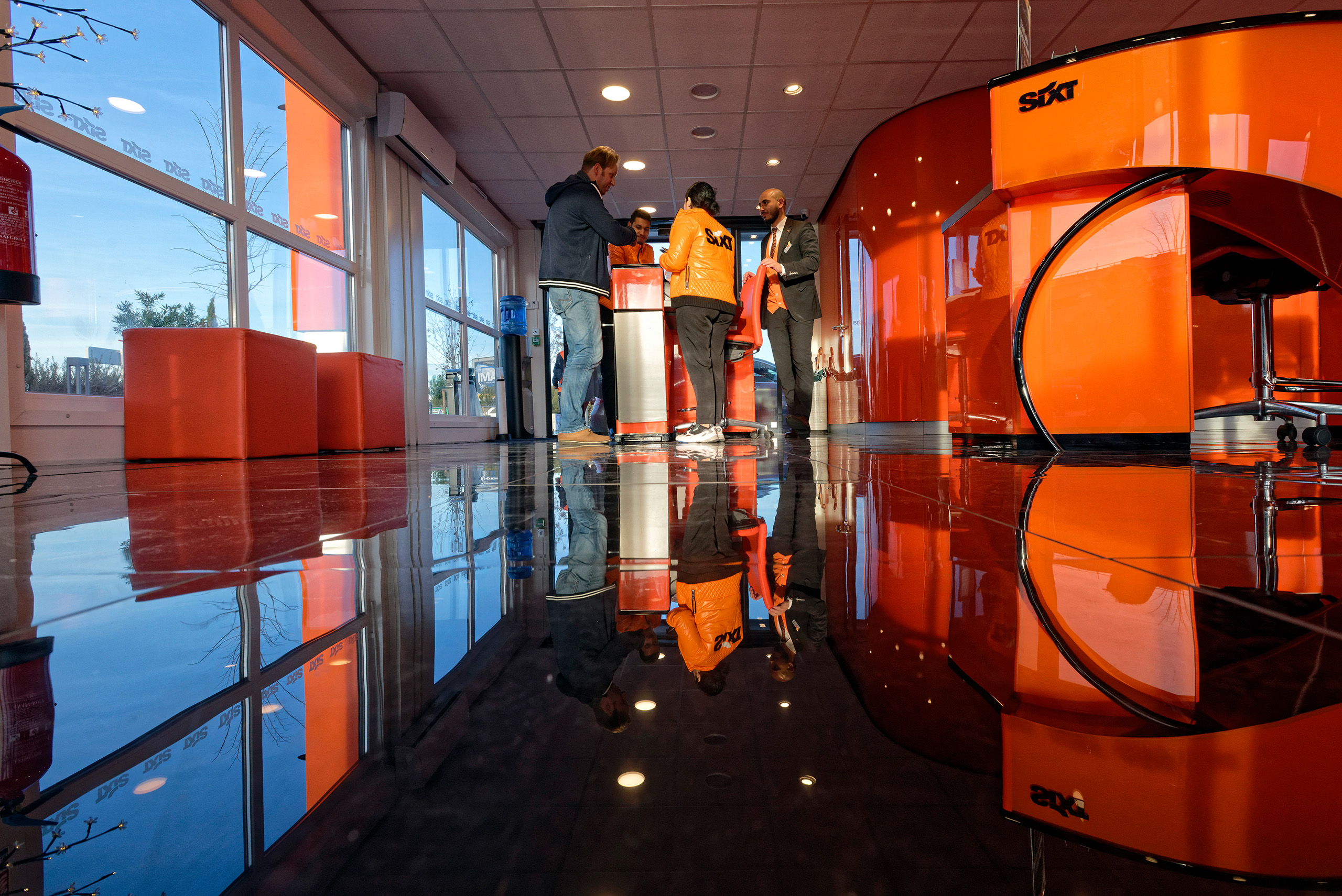intérieur d'un bureau de location de voitures moderne, sol lisse réfléchissant, grandes fenêtres et mobilier orange vif