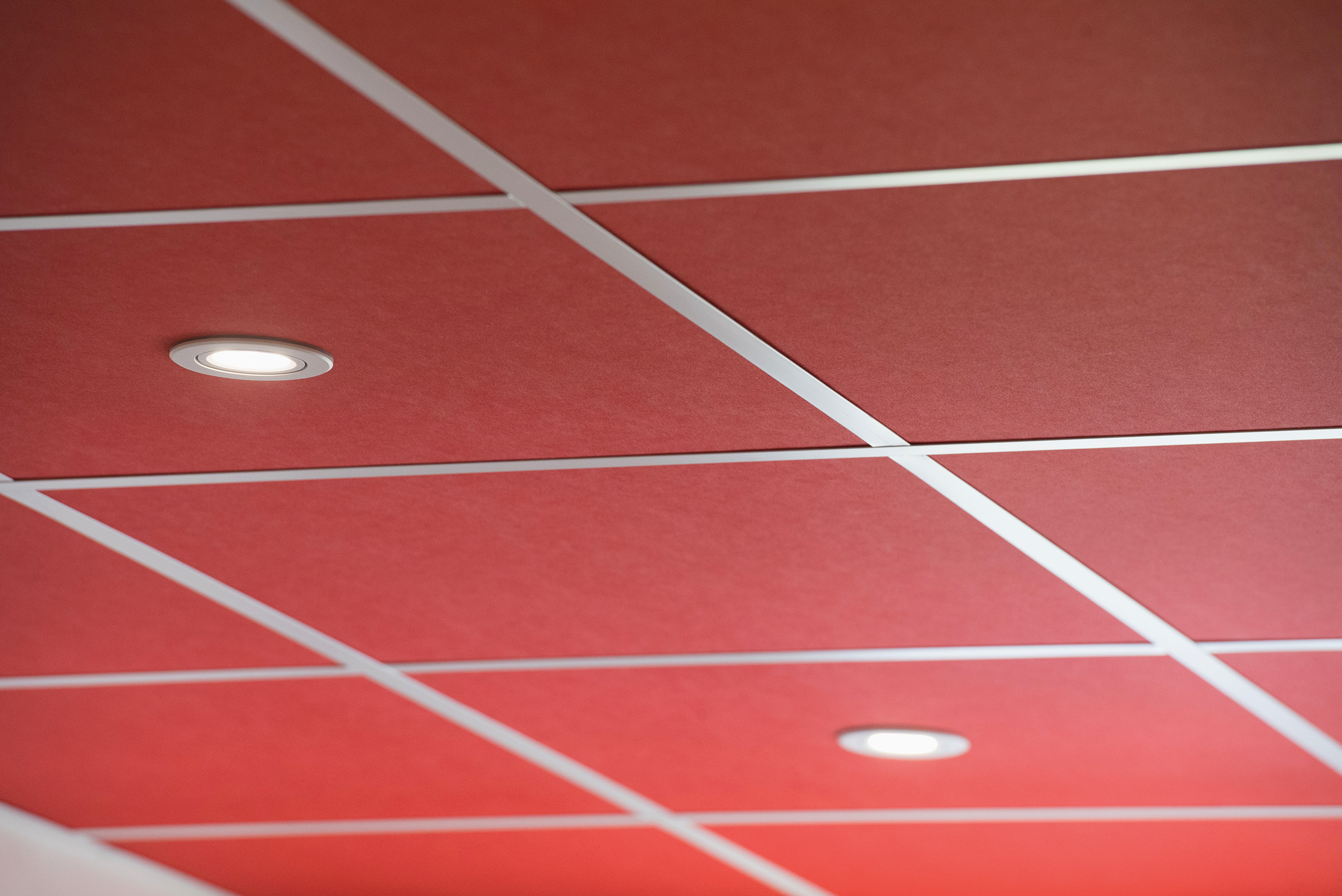 plafond suspendu avec dalles acoustiques rouge foncé et spots encastrés