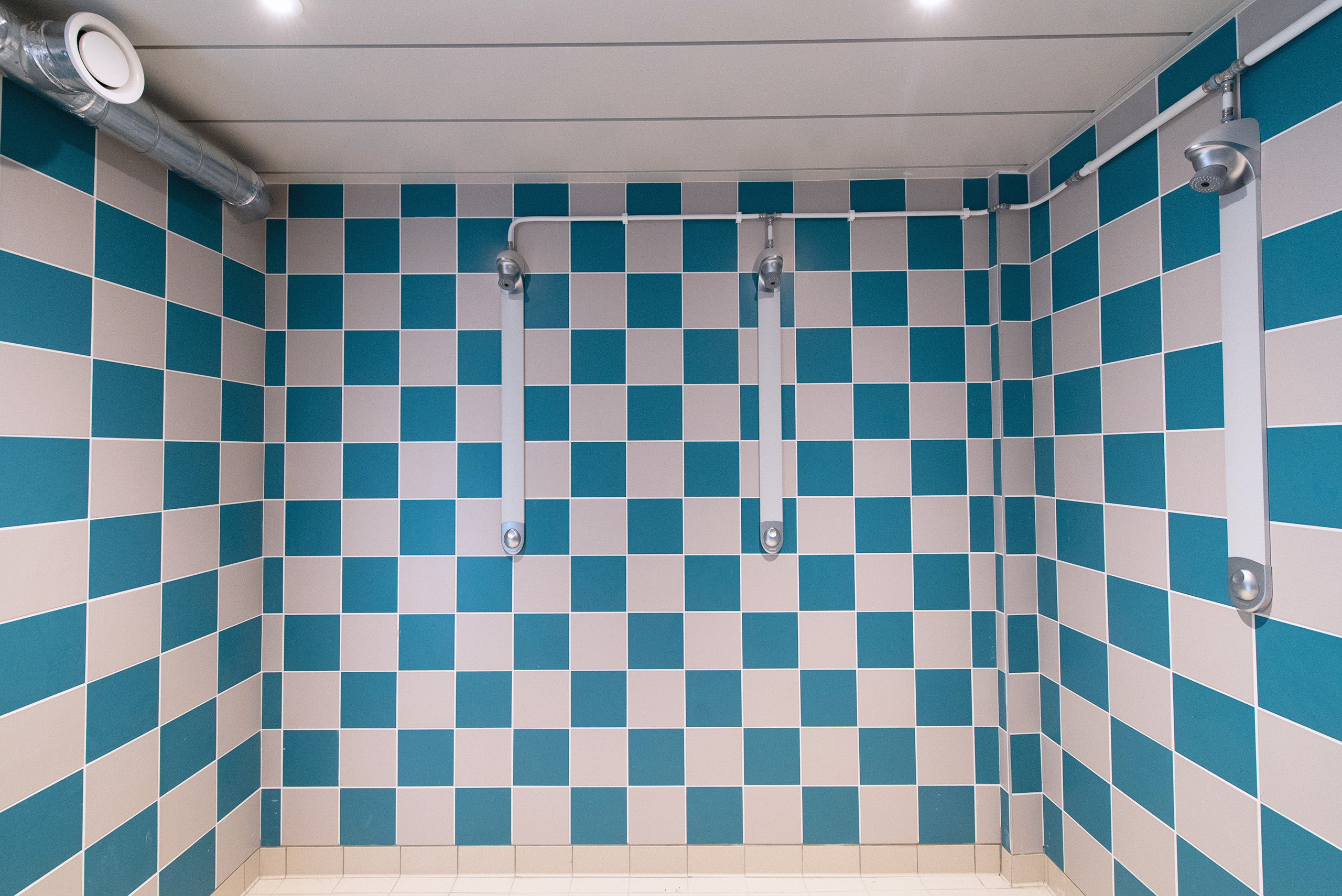 salle de douche collective avec mur carrelé bleu et blanc