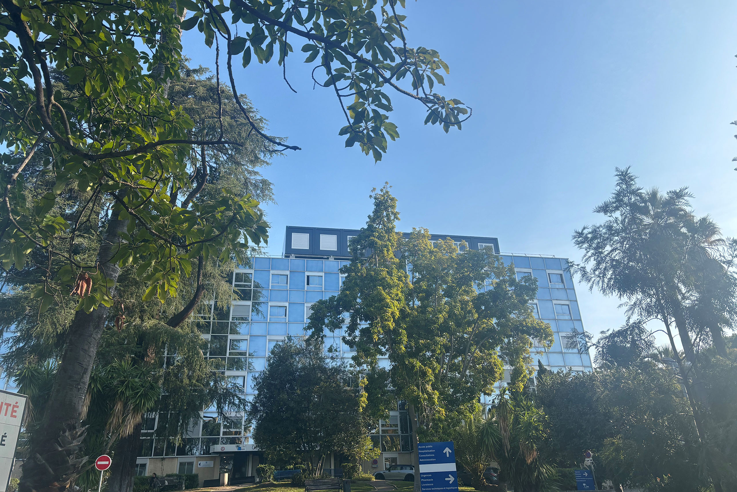 façade de l’hôpital La Palmosa de Menton derrière les arbres avec bureaux modulaires ALGECO® sur le toit