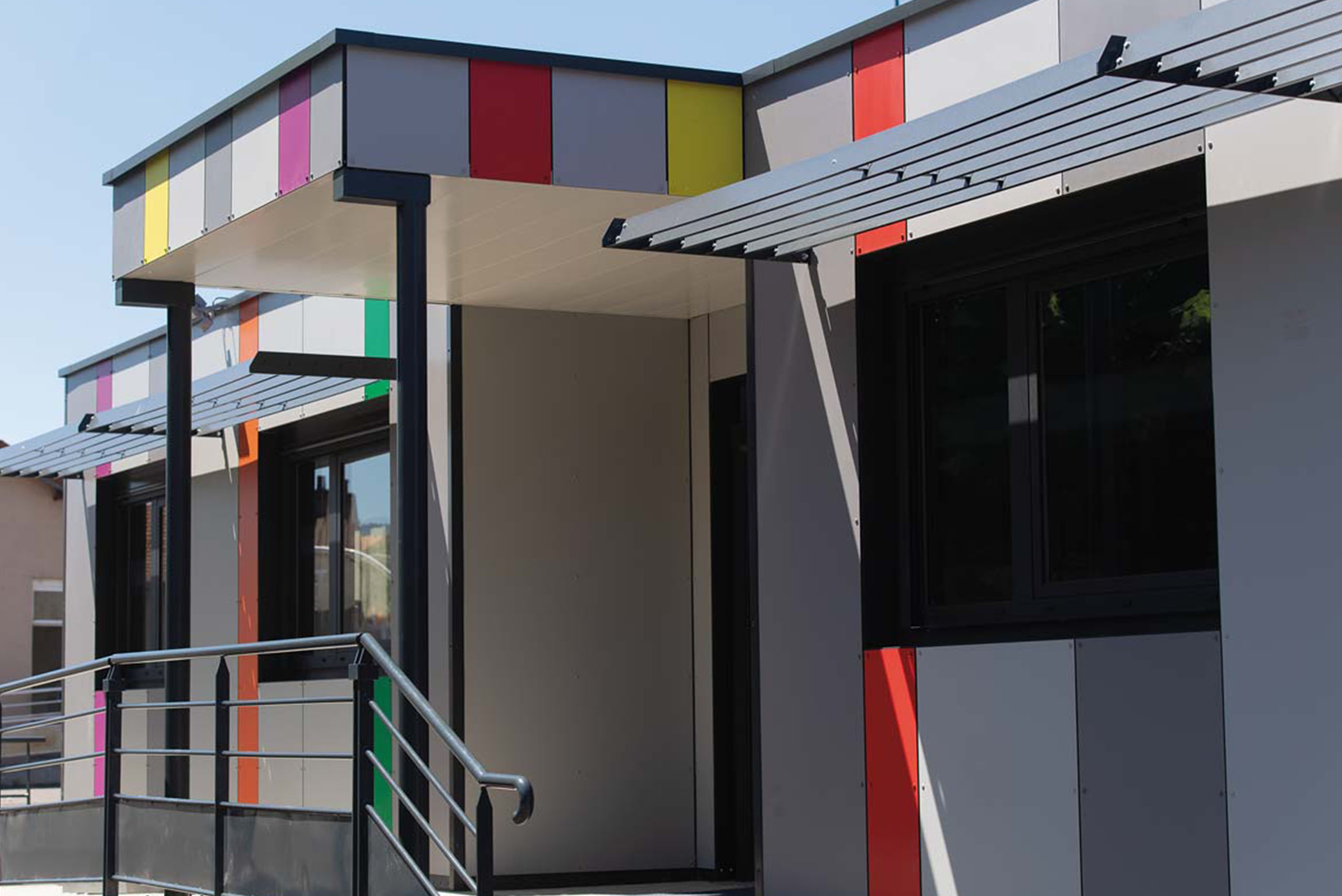 vue extérieure des salles de classe modulaires ALGECO® avec façade colorée, auvent, et rampe d’accès pour l’école primaire de Chanteranne à Clermont Ferrand