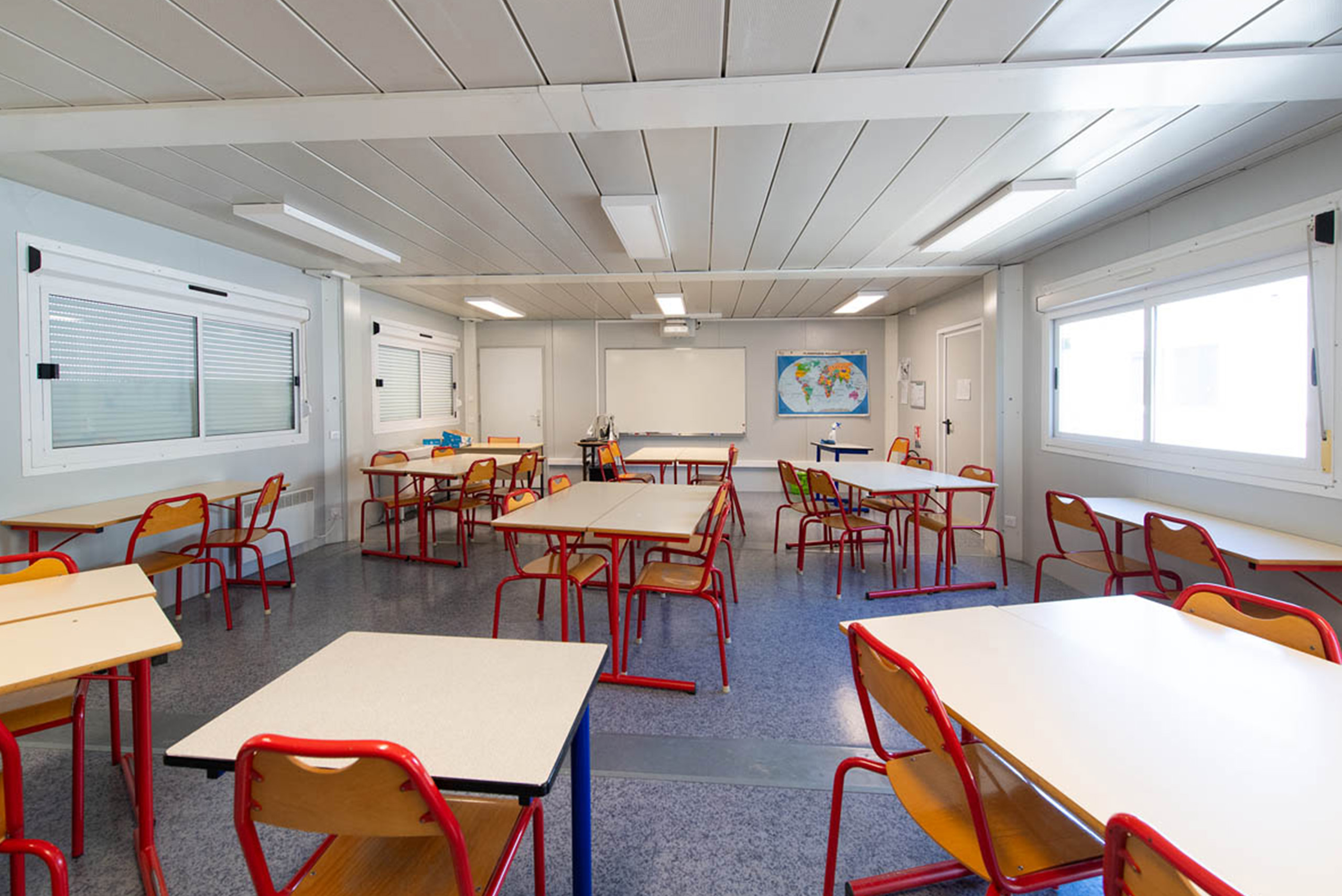 Salle de classe modulaire ALGECO® avec tables et chaises colorées disposées en groupes