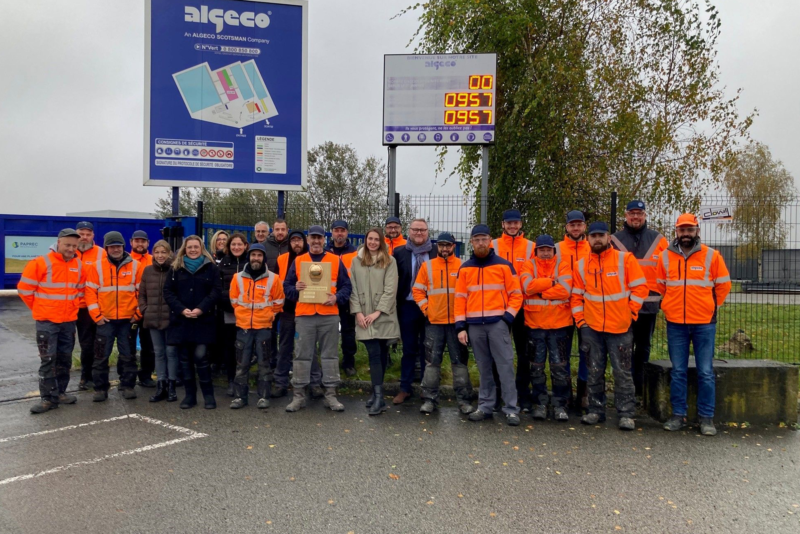 Équipe en tenue de sécurité avec un casque d’or devant un site Algeco