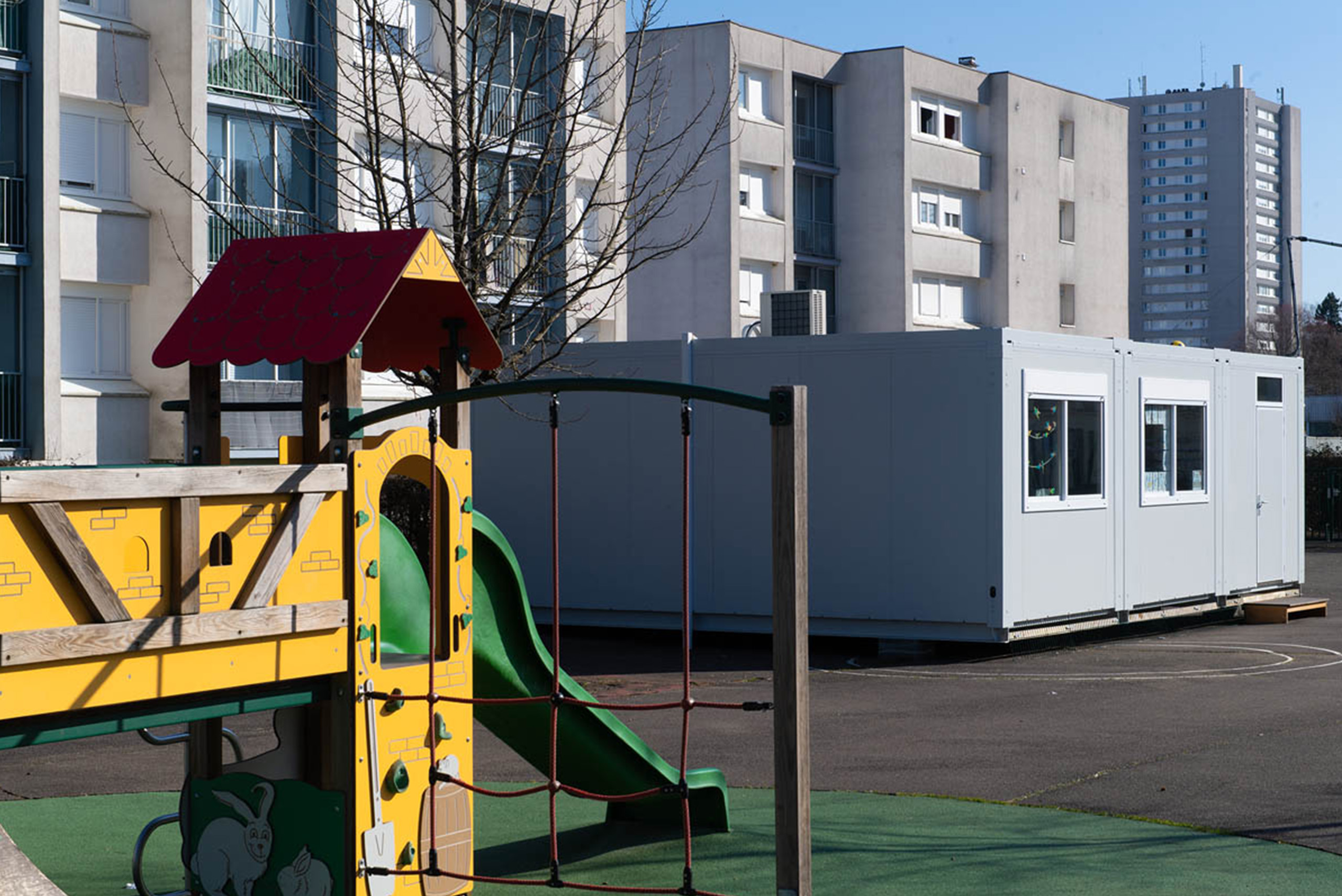 Cour d’école avec structure de jeux et bâtiments modulaire ALGECO® en arrière-plan
