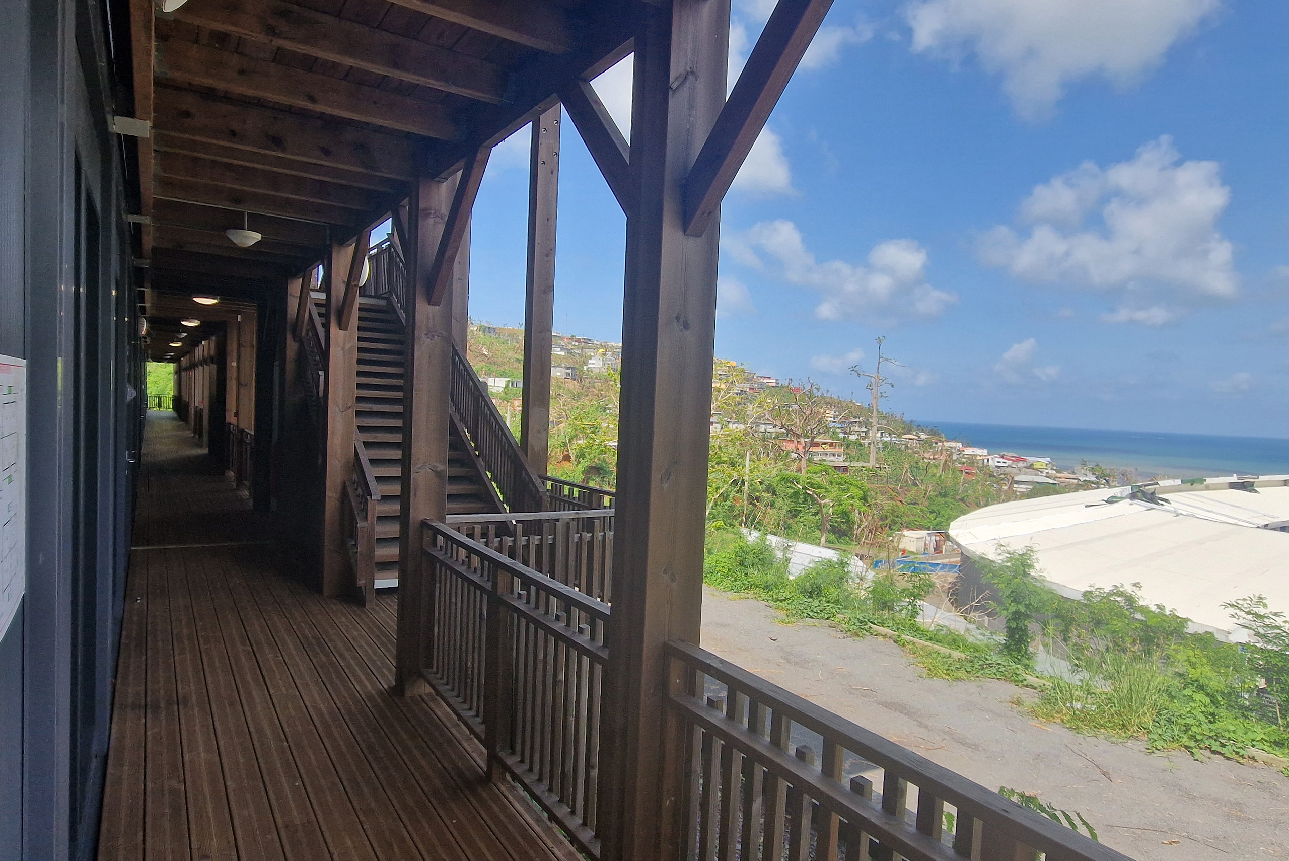 Coursive extérieure en bois d’un bâtiment modulaire ALGECO® scolaire à Mayotte avec vue sur la mer