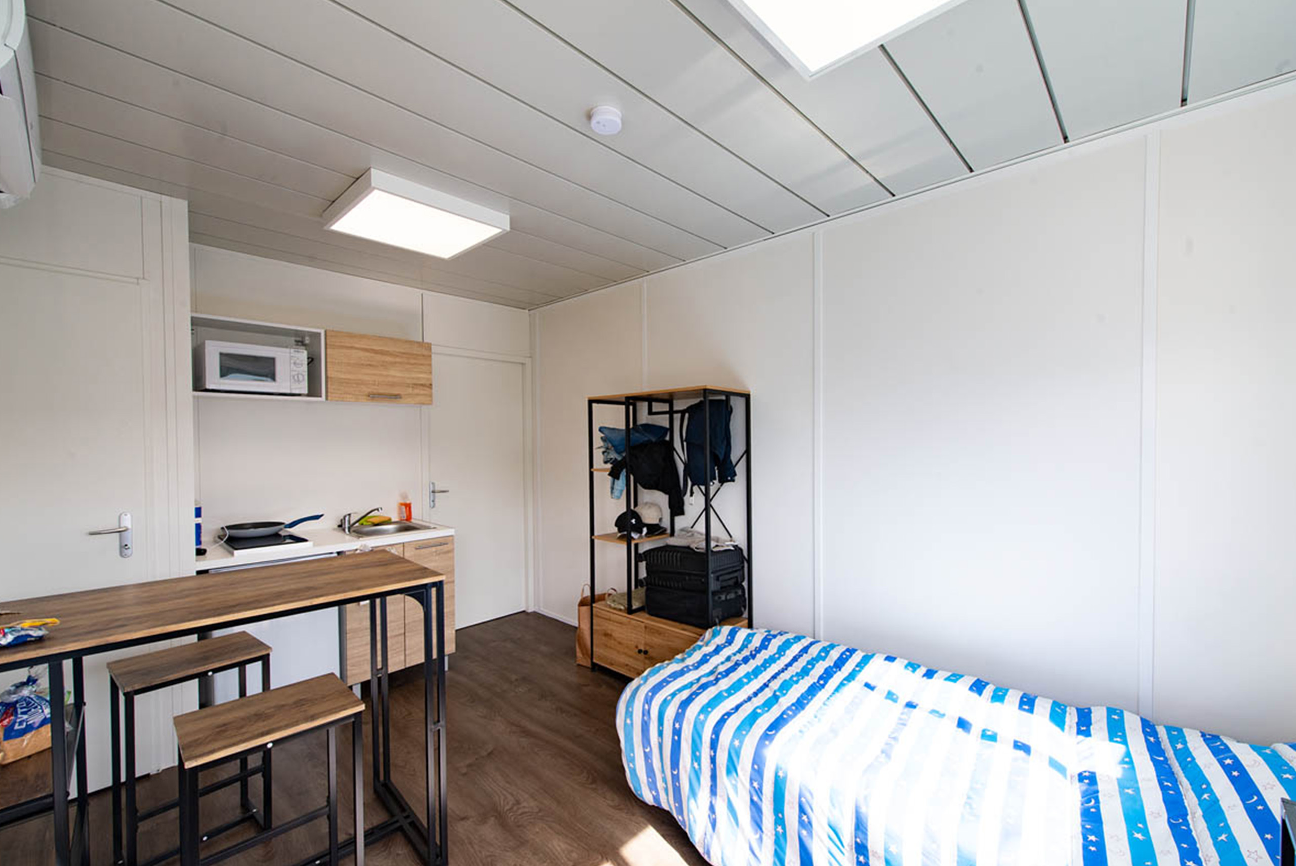 Intérieur d’un studio modulaire ALGECO® avec lit simple, coin cuisine équipé et mobilier fonctionnel à Villenave-d’Ornon