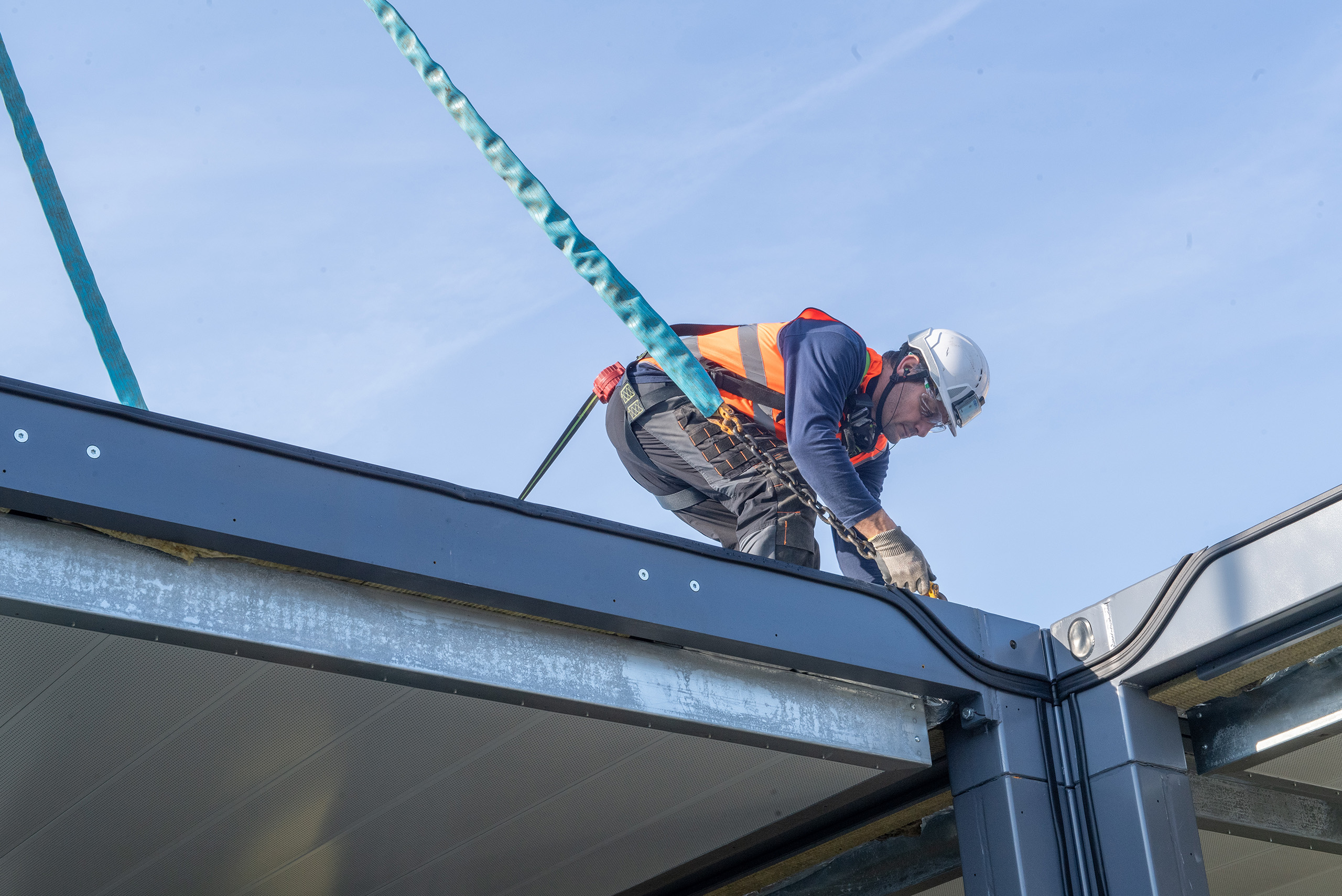 Opérateur en harnais de sécurité travaillant sur l’assemblage d’un module ALGECO® en hauteurLevage d’un module ALGECO® par grue sur un site d’assemblage industriel
