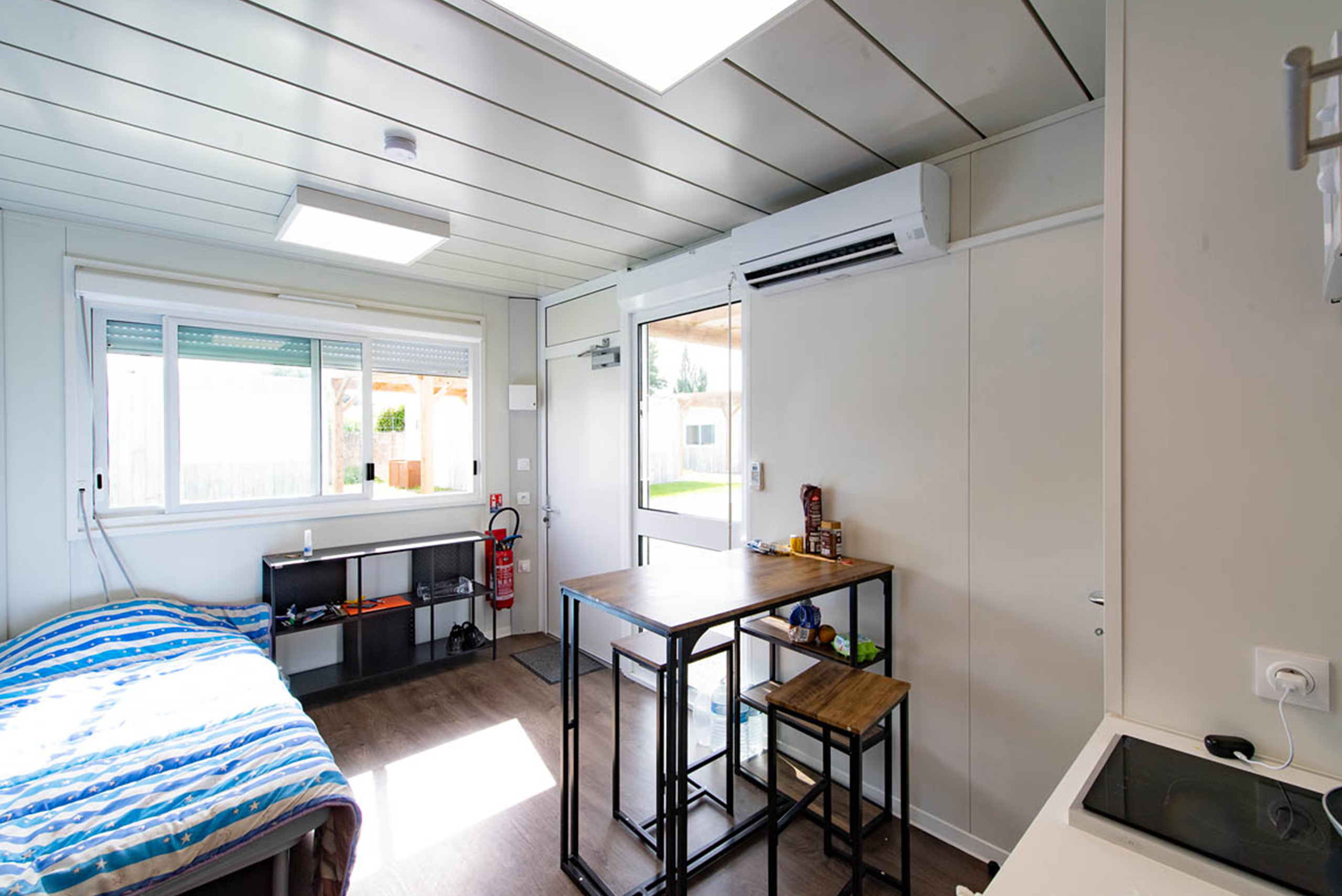 ue depuis l’entrée d’un studio modulaire ALGECO® tout équipé avec lit, table repas, climatisation et grande fenêtre à Villenave-d’Ornon