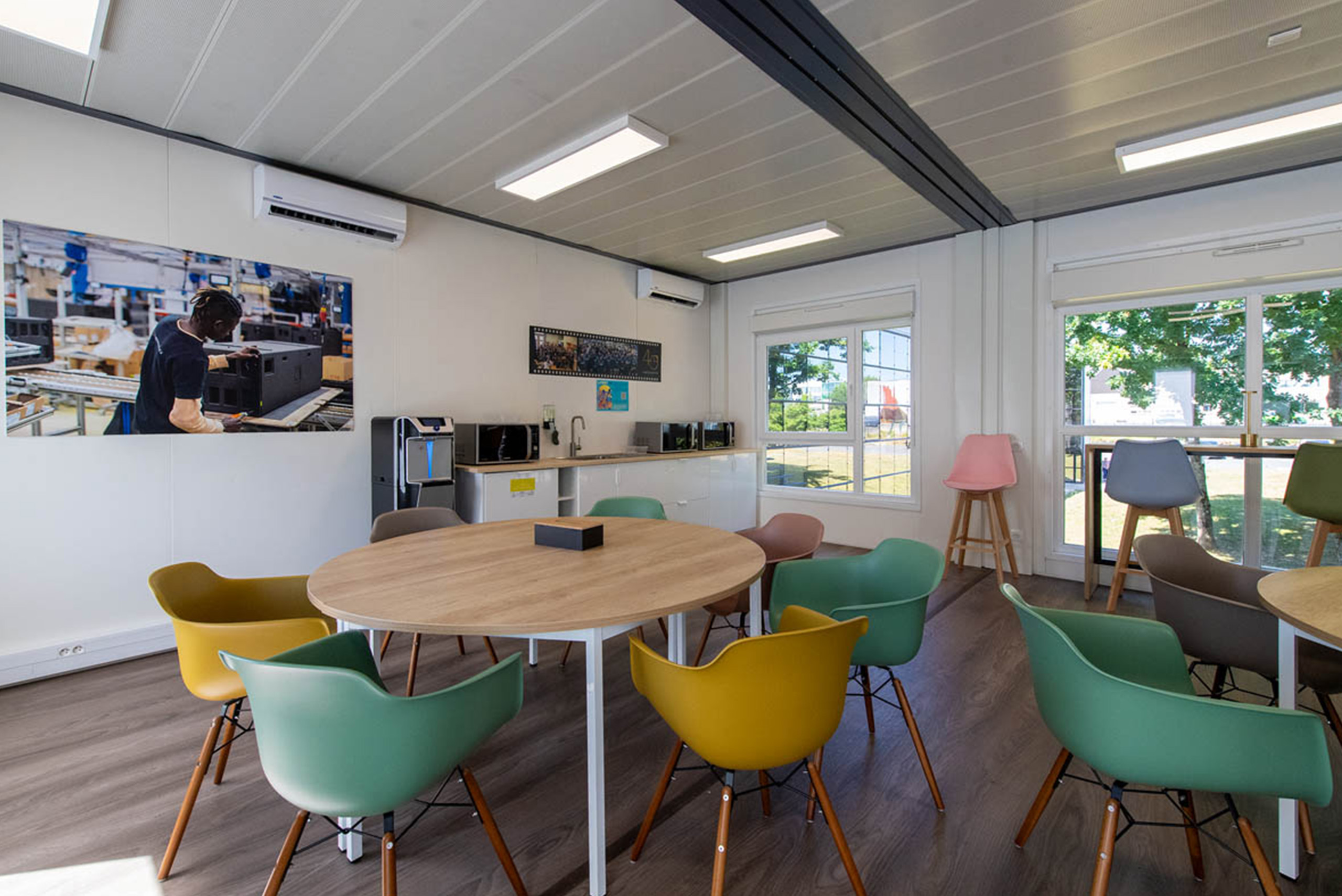 Espace café convivial dans la cafétéria modulaire ALGECO® temporaire de L-Acoustics avec vue sur l’extérieur