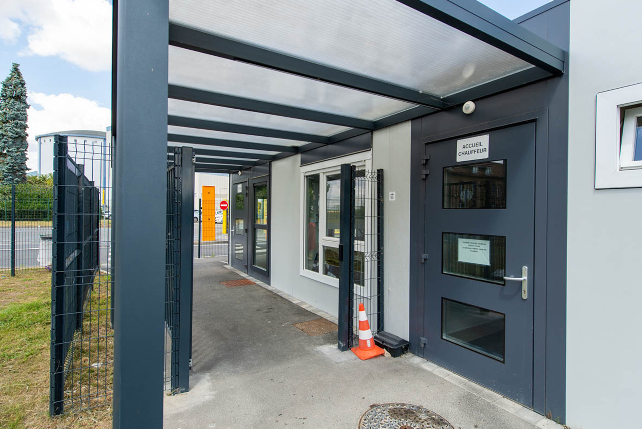 Vue rapprochée de l’entrée du poste de garde modulaire ALGECO® du site Tereos avec auvent et porte vitrée