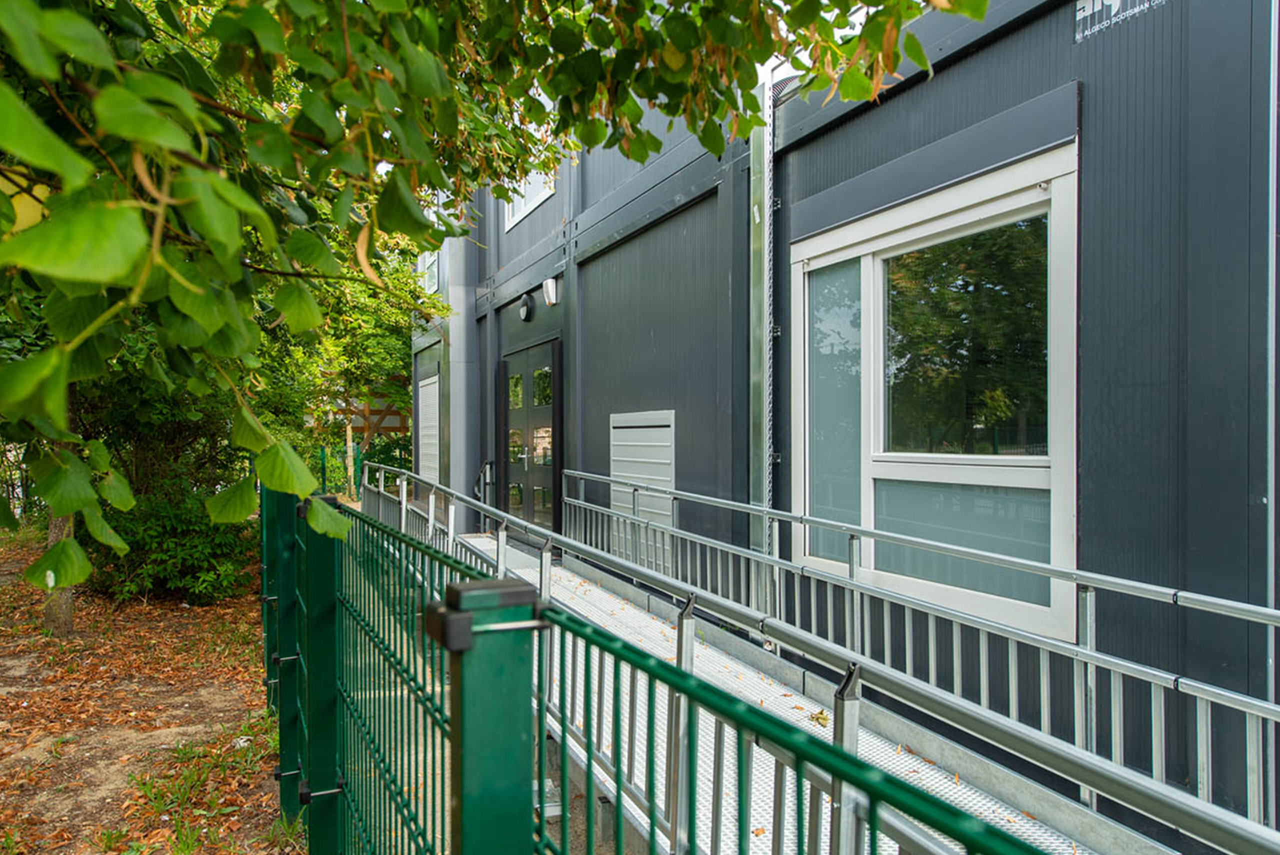 Coursive extérieure d’un bâtiment modulaire ALGECO® en environnement arboré dans une école à Compiegne
