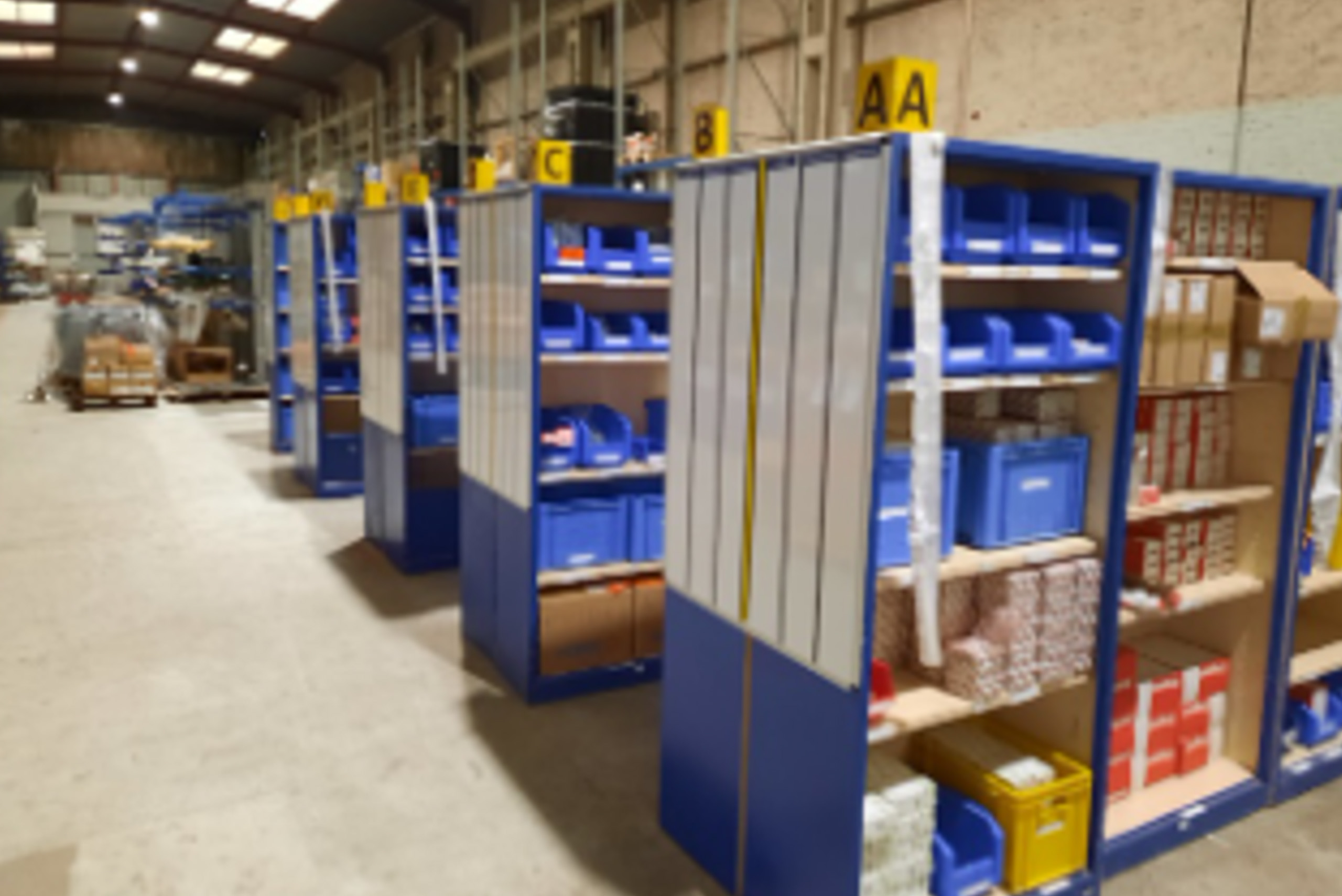 Rayonnages de stockage organisés avec bacs et cartons dans un entrepôt industriel ALGECO®