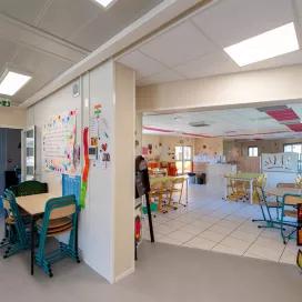 Espace intérieur multi-activités du bâtiment périscolaire modulaire ALGECO® avec mobilier scolaire et décoration colorée