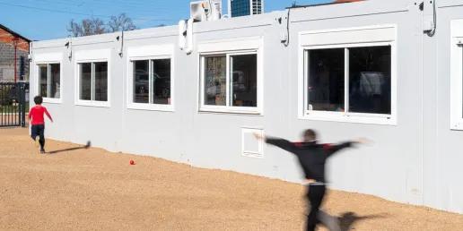 Bâtiment scolaire modulaire ALGECO® blanc avec enfants dans la cour de l’école de Marsat