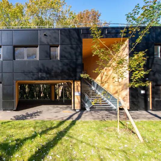 Bâtiment modulaire ALGECO® moderne en façade noire avec escalier extérieur et espaces verts
