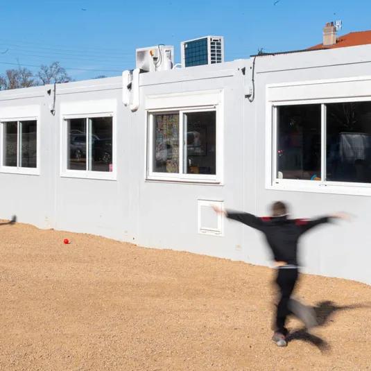 Bâtiment scolaire modulaire ALGECO® blanc avec enfants dans la cour de l’école de Marsat