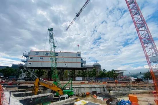 Bâtiment modulaire ALGECO® sur pilotis installé au-dessus d’un chantier urbain avec grues et engins de terrassement