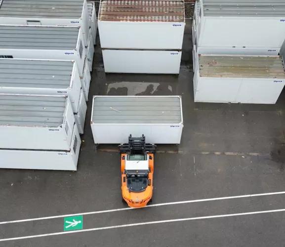 Vue aérienne de blocs modulaires ALGECO® rangés par un chariot élévateur en plein air