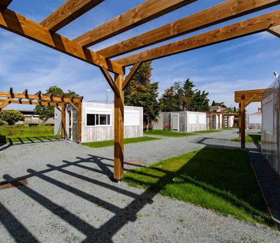Allée paysagère au sein du village modulaire ALGECO® avec pergolas bois et studios indépendants pour demandeurs d’asile à Villenave-d’Ornon