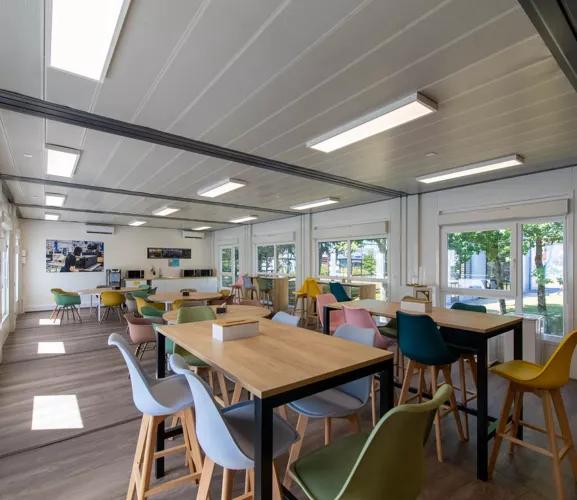 Intérieur lumineux et coloré de la cafétéria modulaire ALGECO® temporaire de l’entreprise L-Acoustics à Marcoussis