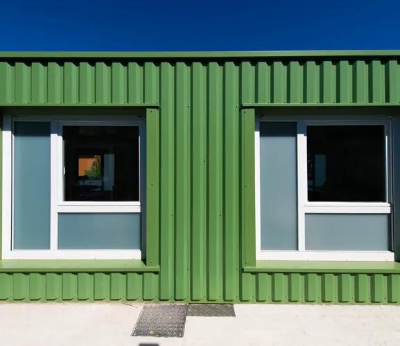 Façade verte de salles de classe modulaires ALGECO® ENILEA avec fenêtres à Mamirolle