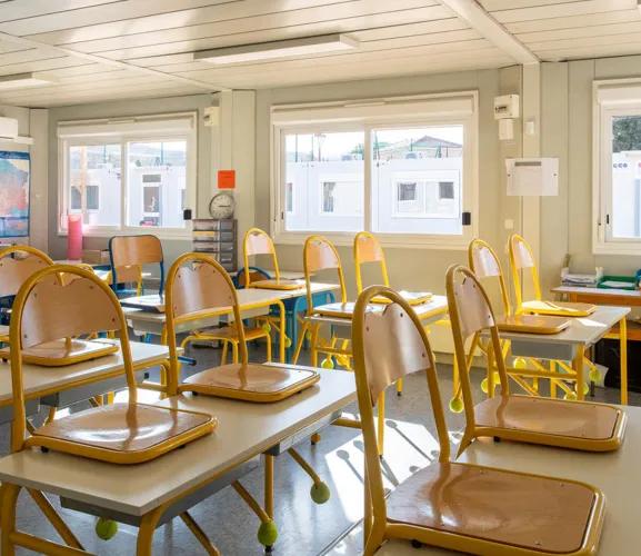 Salle de classe modulaire ALGECO® lumineuse avec chaises posées sur les tables