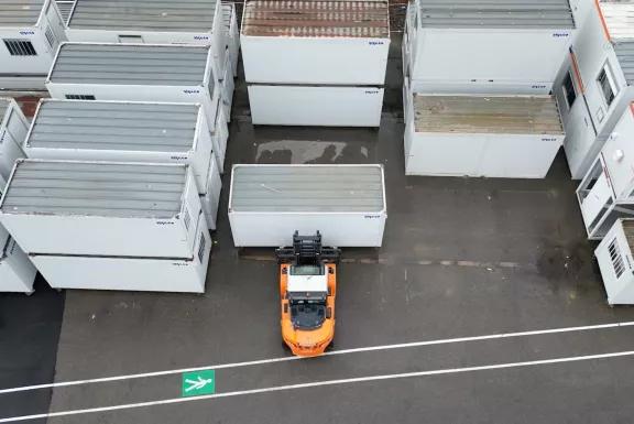 Vue aérienne de blocs modulaires ALGECO® rangés par un chariot élévateur en plein air