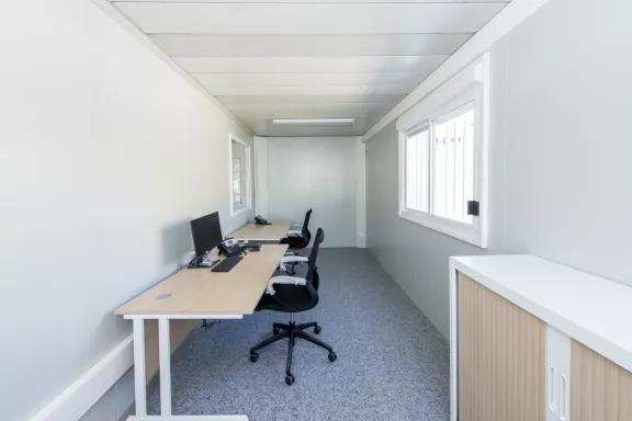 Espace de travail fonctionnel dans un bureau modulaire d’occasion ALGECO® avec deux postes équipés.