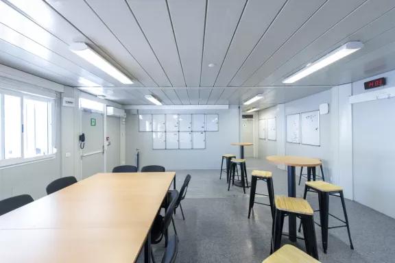 Intérieur d’un bureau modulaire d’occasion ALGECO® aménagé avec espace de réunion et tables hautes