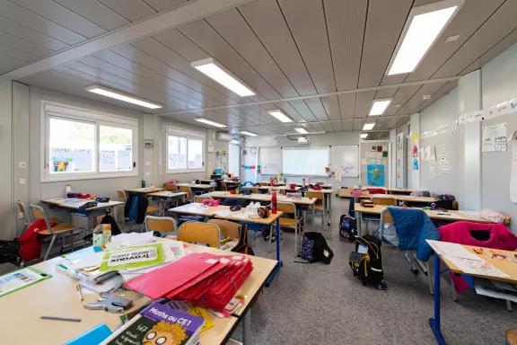 Intérieur d’une salle de classe modulaire ALGECO® avec pupitres et matériel scolaire