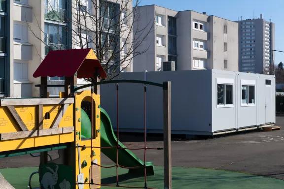Salle de classe modulaire ALGECO® blanche en zone urbaine avec aire de jeux