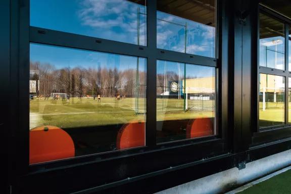 Vue depuis l’extérieur d’un centre d’entraînement modulaire ALGECO® à Pau avec reflet du terrain de football
