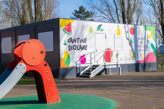 Cantine scolaire modulaire Algeco décorée avec des illustrations de fruits et légumes colorés