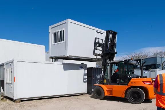 Manutention d’un module modulaire ALGECO® reconditionné à l’aide d’un chariot élévateur sur une plateforme logistique
