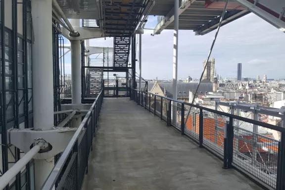 Passerelle extérieure sur chantier en hauteur avec vue panoramique sur les toits de Paris par Altempo