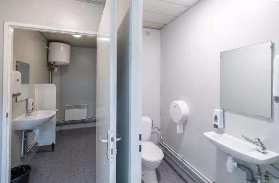 Bloc sanitaire de chantier équipé de WC, lavabos, miroir et distributeurs muraux