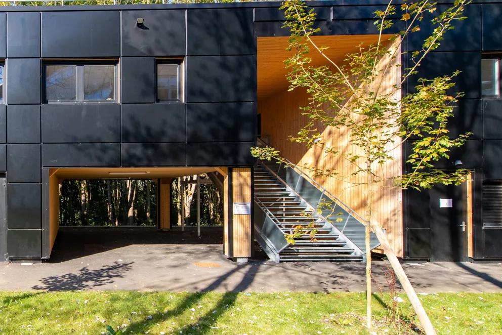 Bâtiment modulaire ALGECO® moderne en façade noire avec escalier extérieur et espaces verts