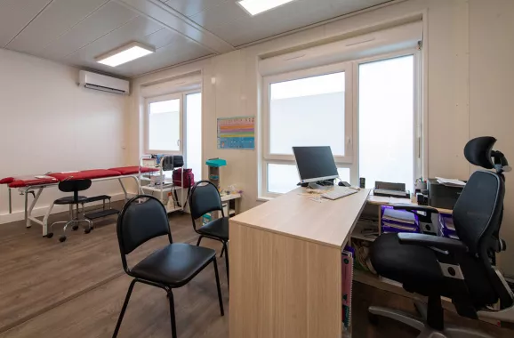 Cabinet médical modulaire ALGECO® avec banc, bureaux, ordinateur, climatisation et fenêtre entrée sur la gauche