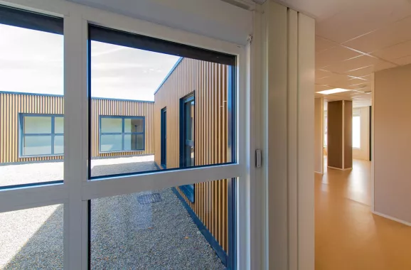 vue intérieure et extérieure de bâtiments modulaires avec bardage bois et métal, couloir blanc et beige