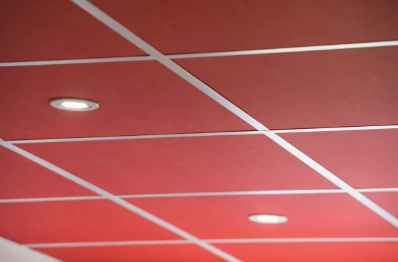 plafond suspendu avec dalles acoustiques rouge foncé et spots encastrés