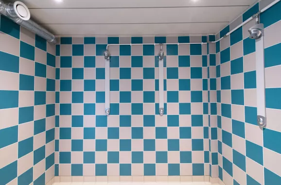 salle de douche collective avec mur carrelé bleu et blanc
