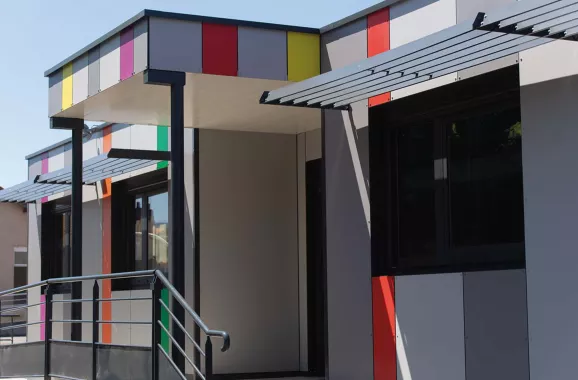 vue extérieure des salles de classe modulaires ALGECO® avec façade colorée, auvent, et rampe d’accès pour l’école primaire de Chanteranne à Clermont Ferrand