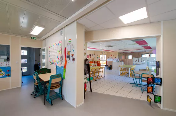 Espace intérieur multi-activités du bâtiment périscolaire modulaire ALGECO® avec mobilier scolaire et décoration colorée
