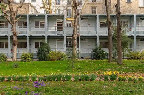 Façade du bâtiment modulaire ALGECO® à deux niveaux, intégrée au jardin fleuri de l’Institut catholique de Paris