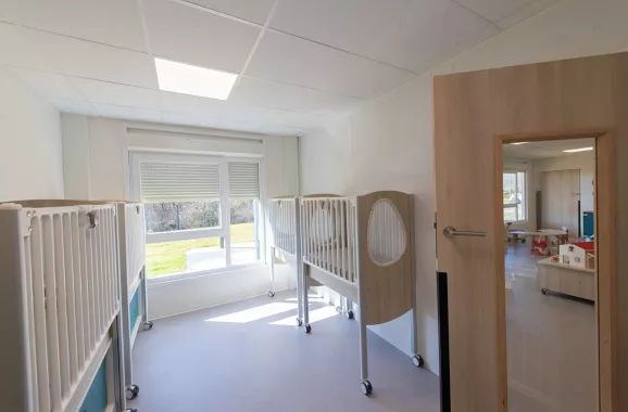 Salle de repos pour enfants dans la crèche modulaire ALGECO® à Messigny-et-Vantoux avec lits à barreaux et lumière naturelle