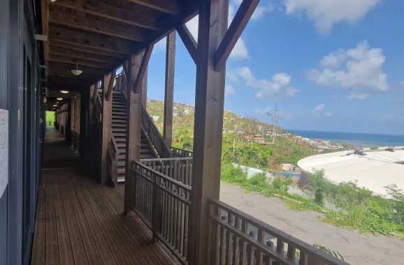 Coursive extérieure en bois d’un bâtiment modulaire ALGECO® scolaire à Mayotte avec vue sur la mer